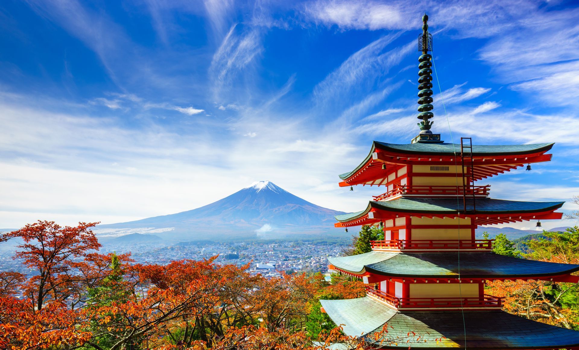A pagoda with a mountain in the background and a city in the foreground.