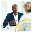 a man in a suit is sitting at a table talking to a woman .