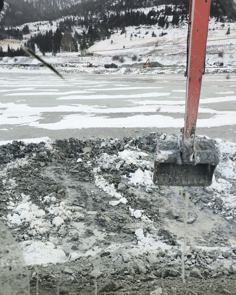 An excavator is digging a hole in the ground near a body of water