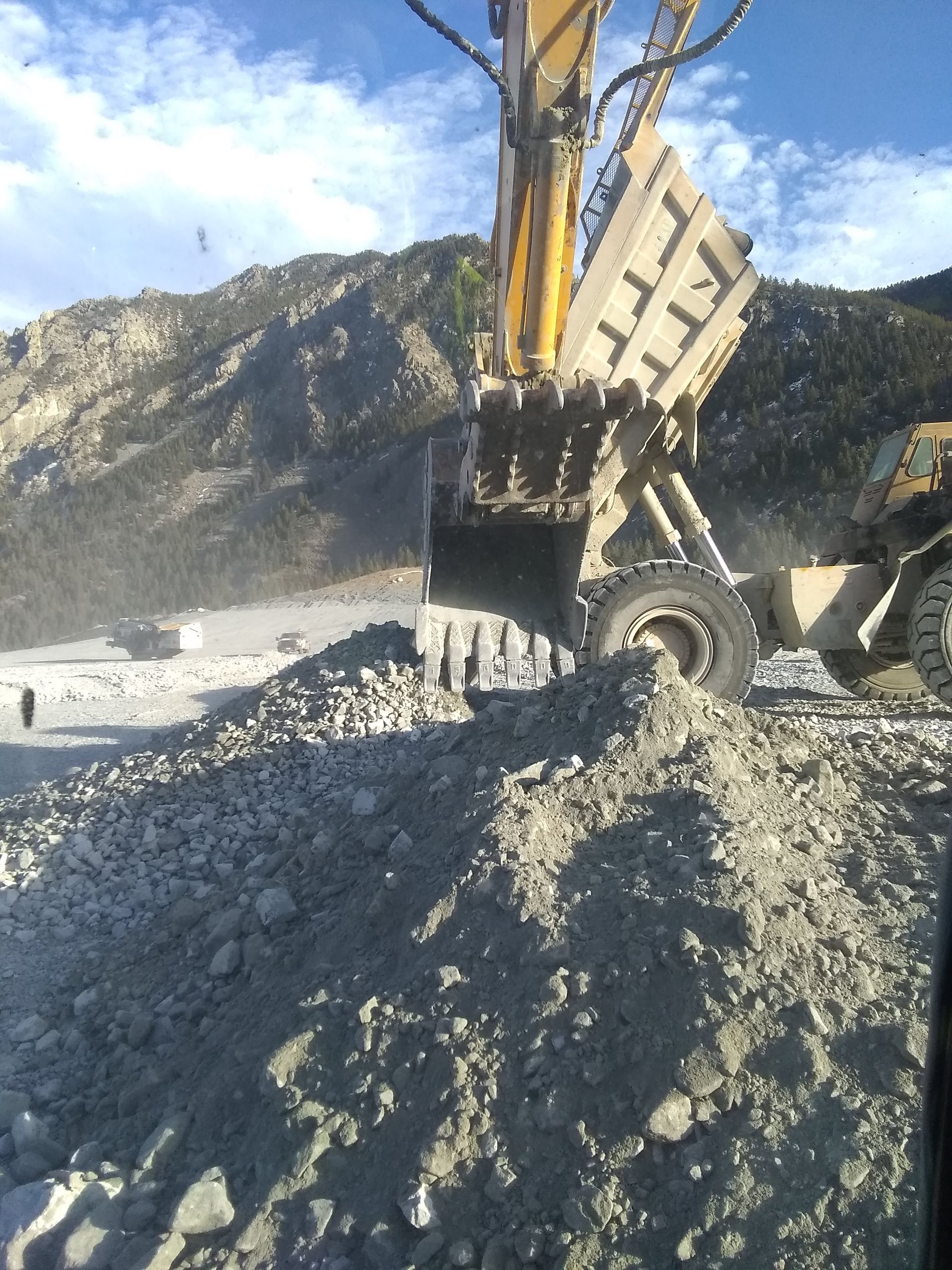 A yellow excavator is loading dirt into a dump truck