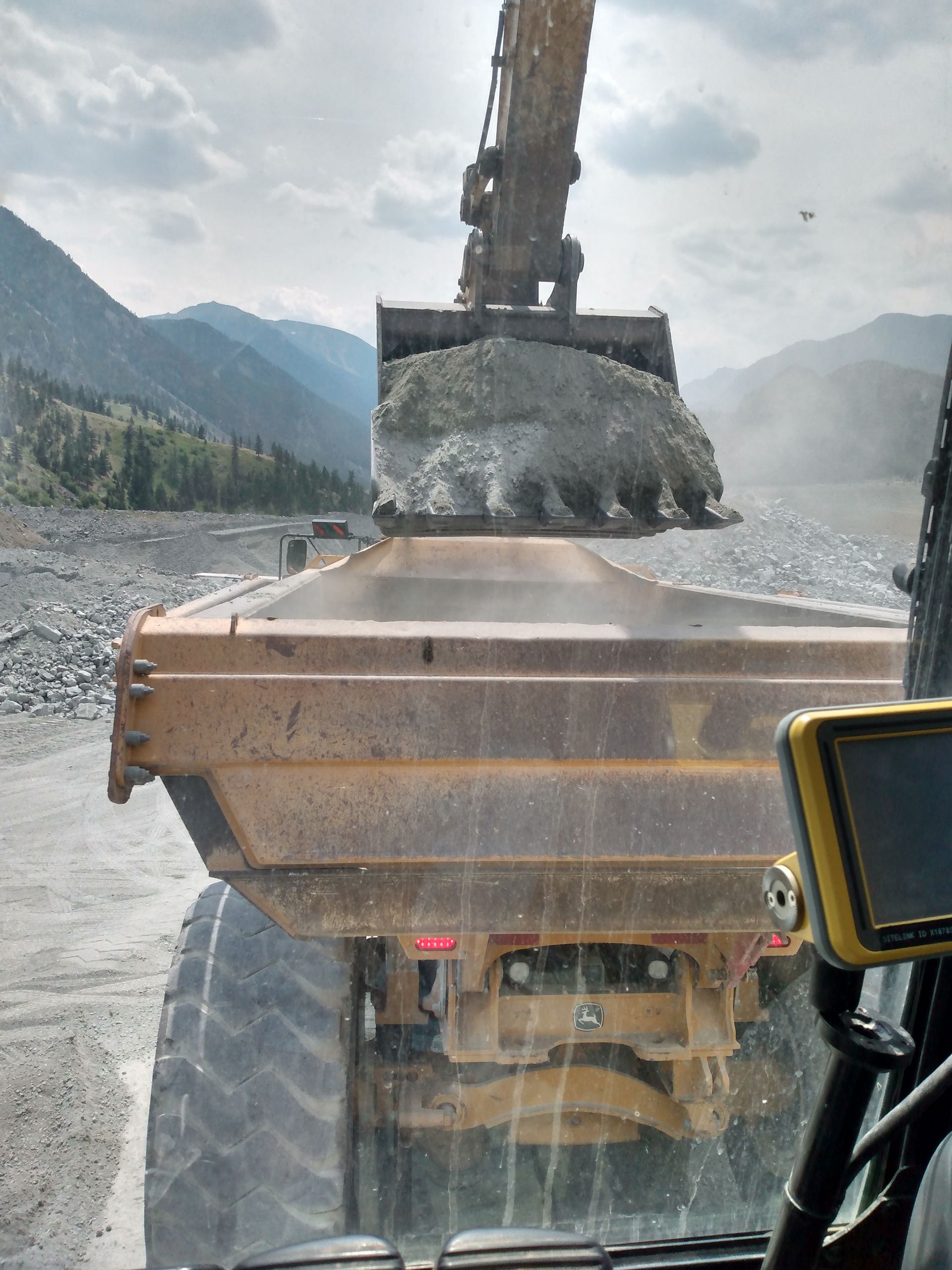 A dump truck is being loaded with rocks by an excavator