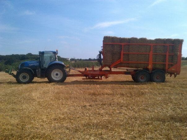 tractor towing bales of hay on trailer