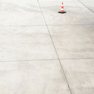 An orange and white traffic cone on a concrete surface