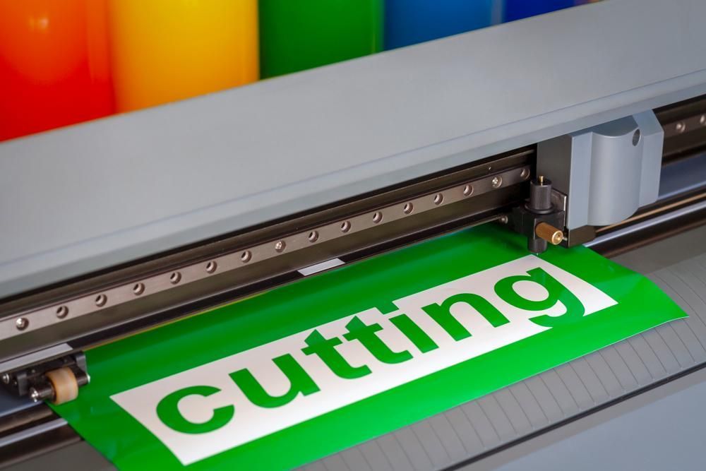 A Cutting Machine Is Cutting a Green Piece of Paper — Brookes Engraving & Signs in Unanderra, NSW