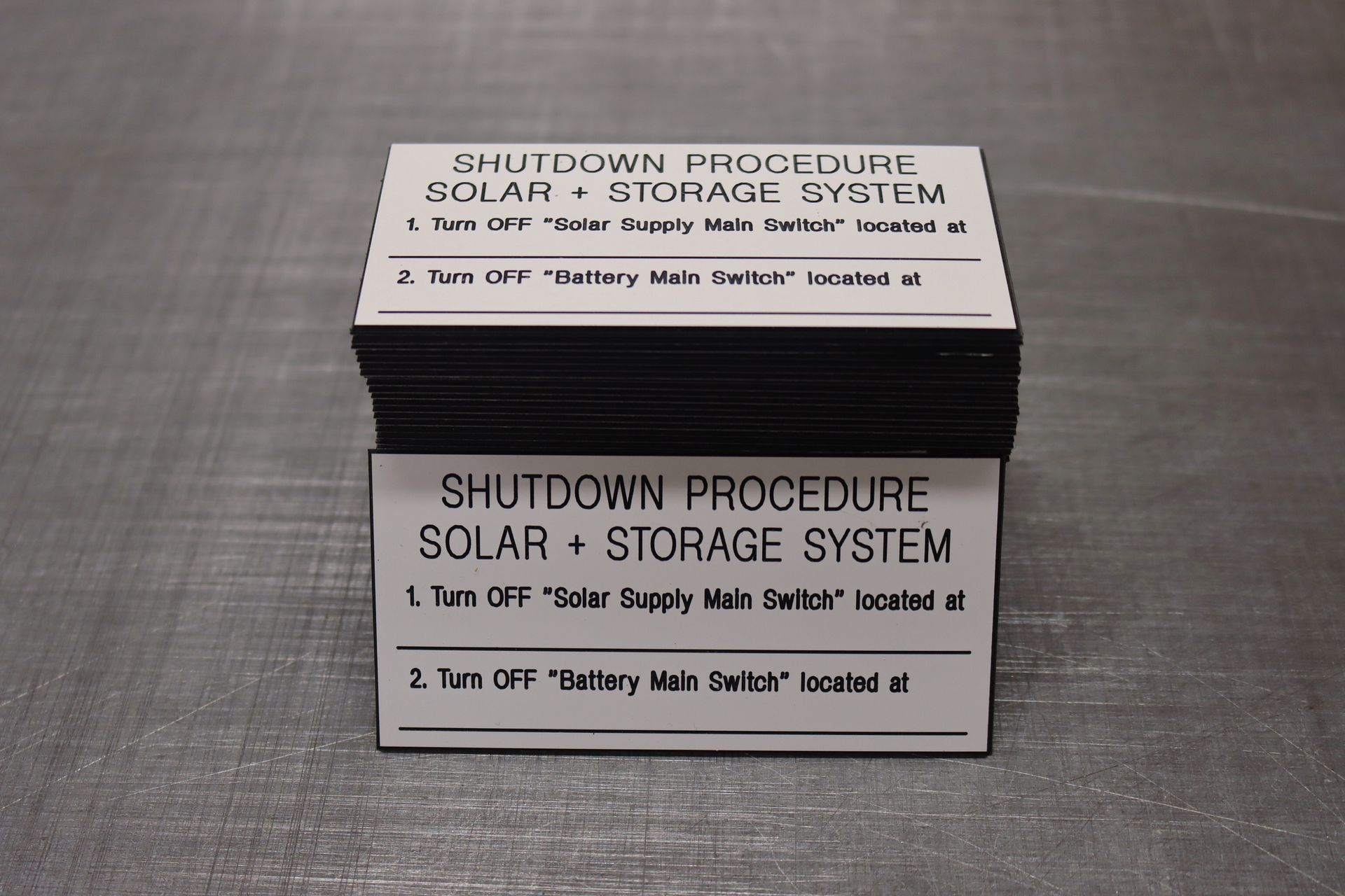 A stack of shutdown procedure solar + storage system labels — Brookes Engraving & Signs in Woonona, NSW