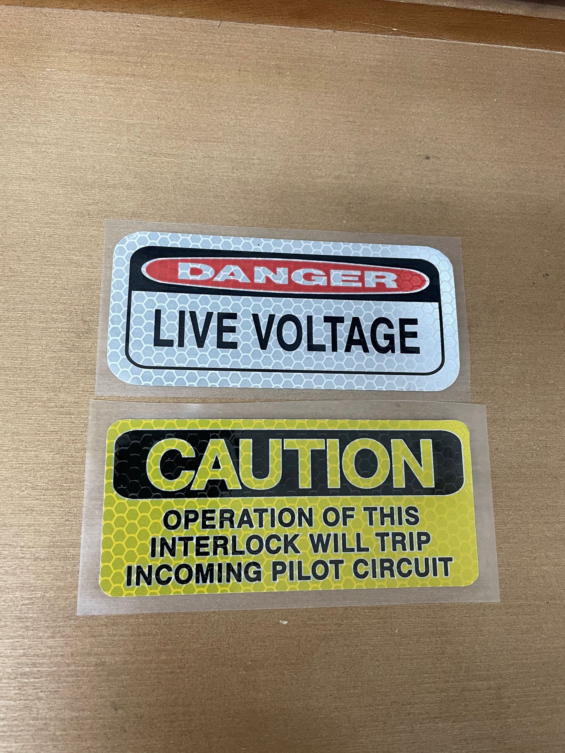 Two stickers that say danger live voltage and caution operation of this interlock will trip incoming pilot circuit