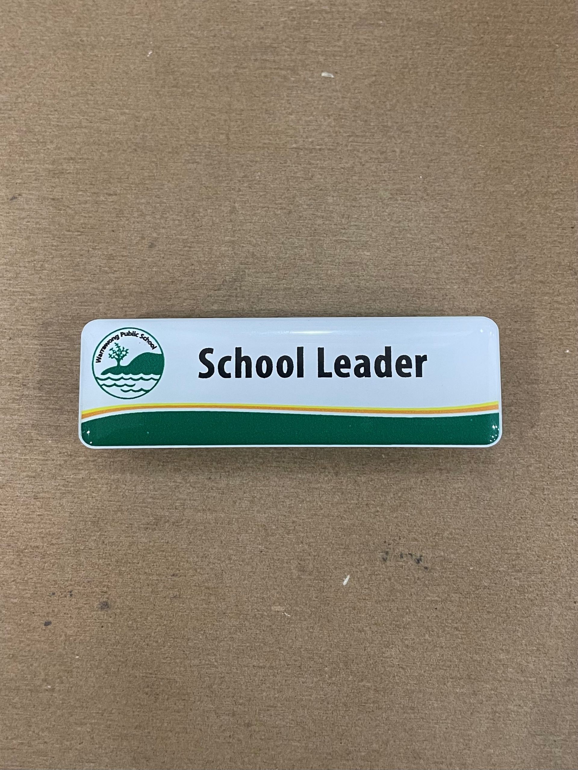 A school leader name tag is sitting on a wooden table. — Brookes Engraving & Signs in Woonona, NSW