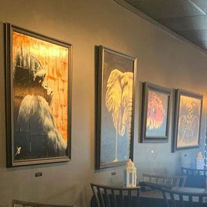Artwork of an ape, elephant, and flower, framed on a dark wall in a room.