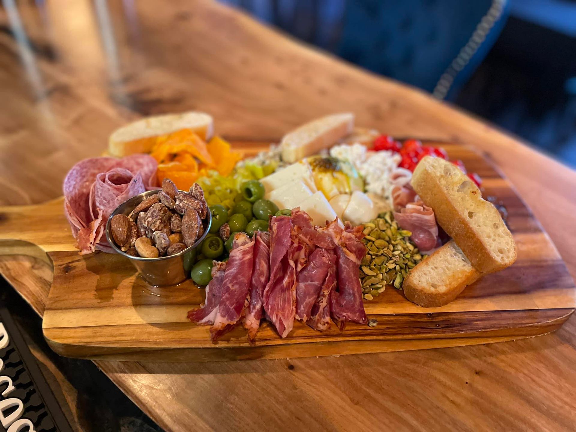 Charcuterie board with meats, cheeses, olives, bread, and nuts on a wooden platter.