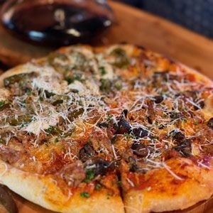 Pizza with toppings, cut into slices, topped with green peppers, cheese, and sausage.