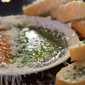 Dish of dip topped with grated cheese, served with garlic bread.