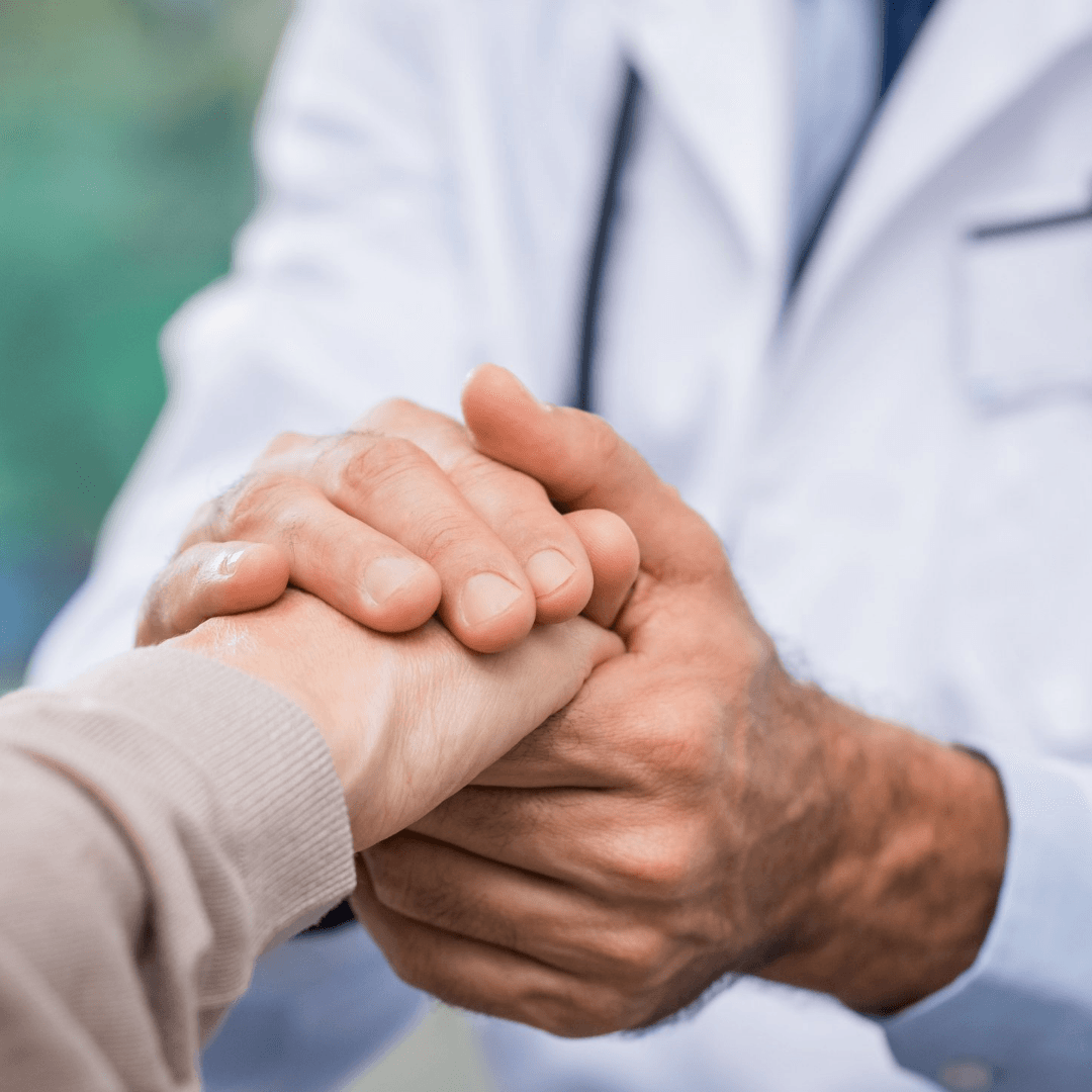 Internal medicine doctor holding elderly patient's hand.