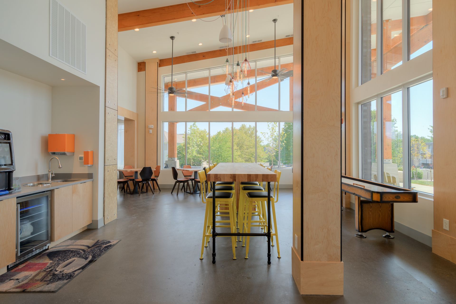 A modern kitchen with a breakfast bar, stools, stainless steel appliances, and pendant lights.