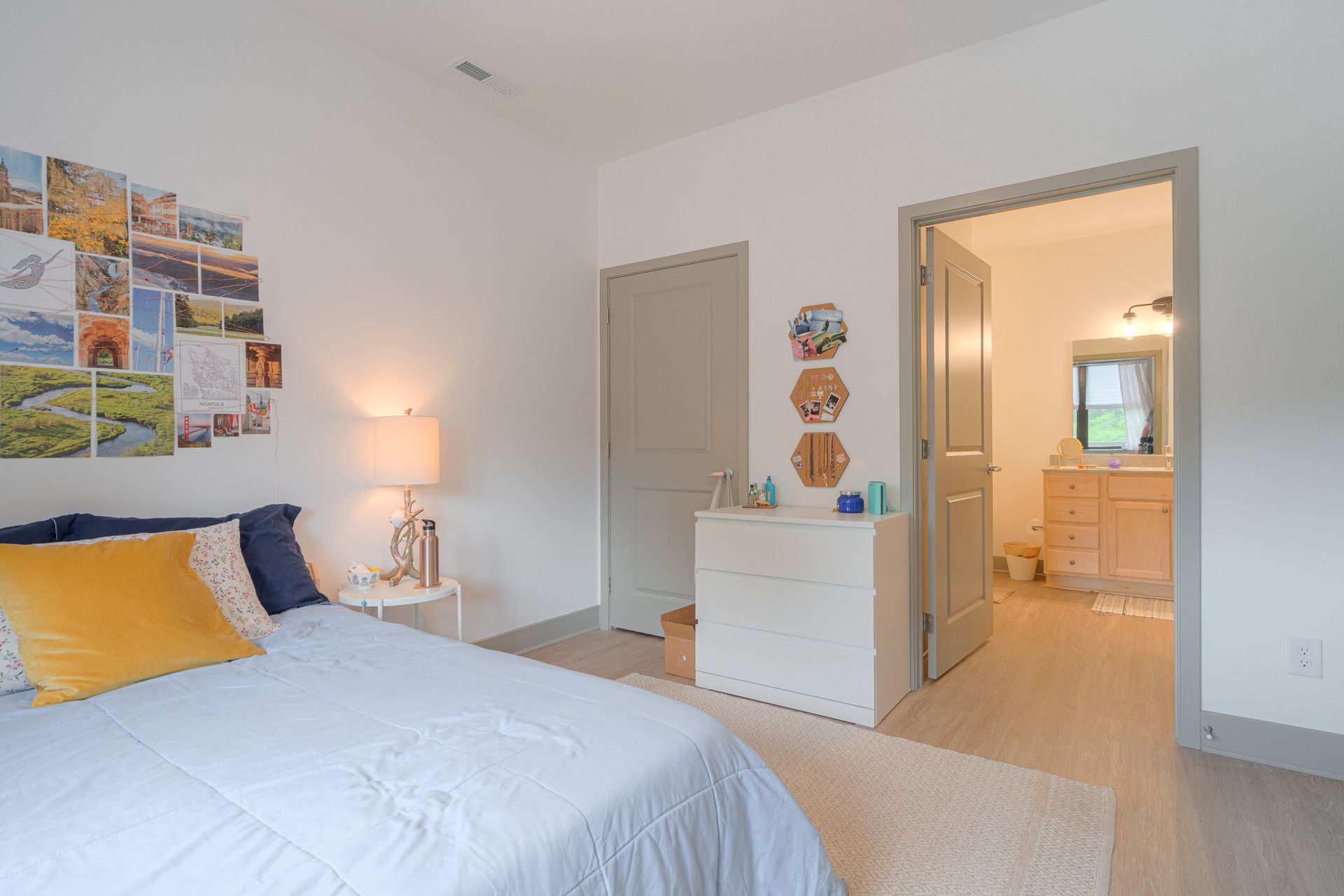 Bedroom with bed, dresser, door to bathroom, and wall decor.