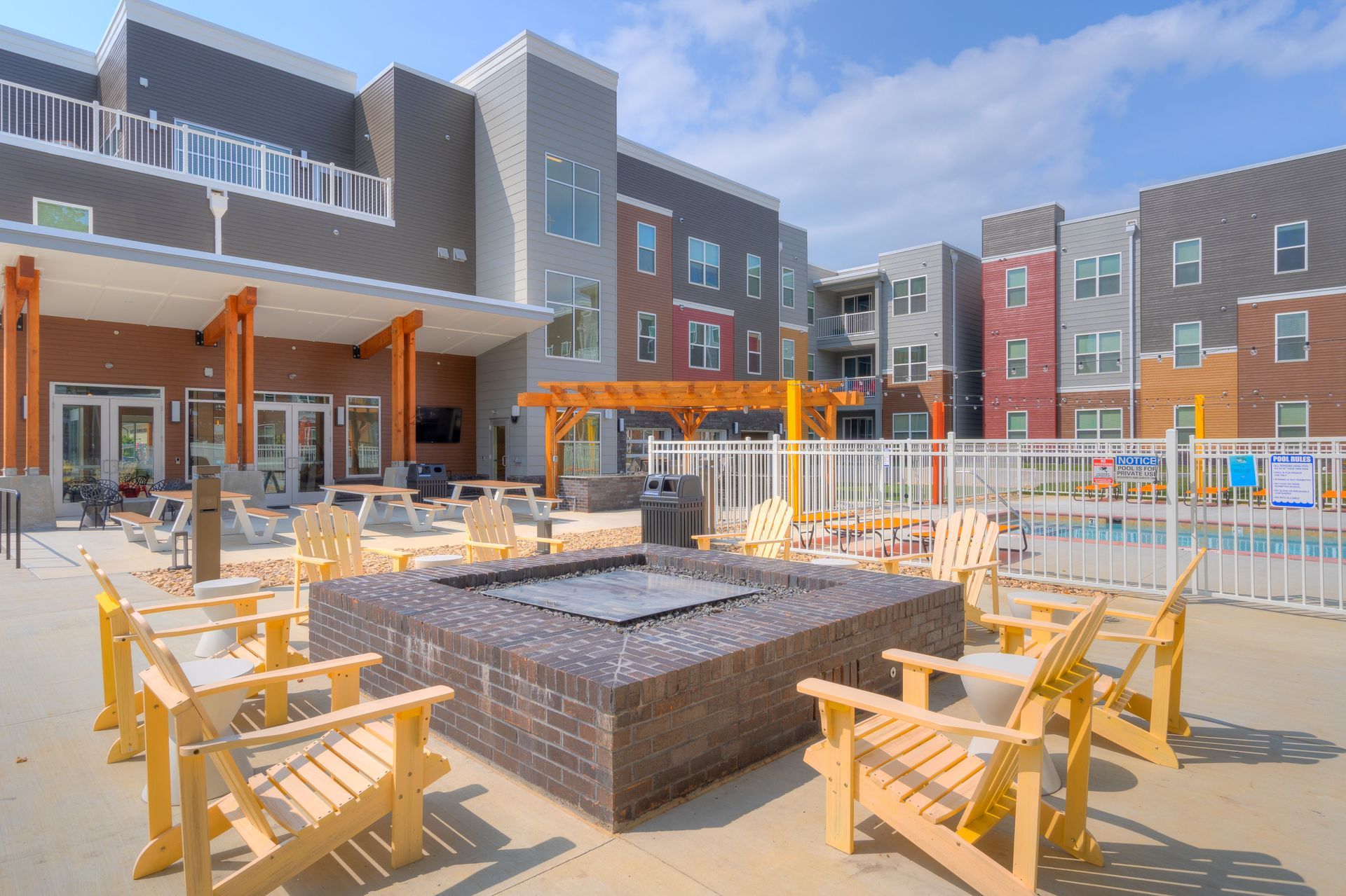 Living room with sofa, coffee table, and kitchen in the background. Beach scene artwork on the wall.
