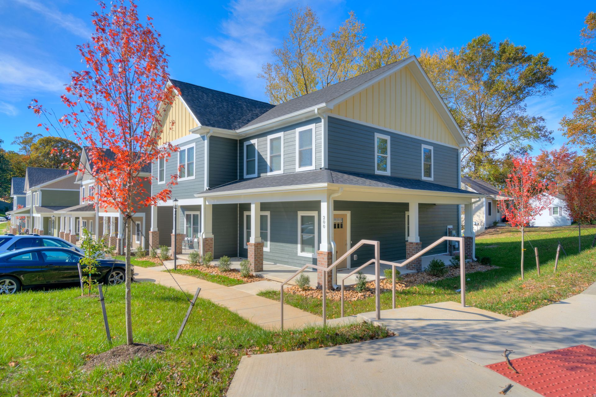 Two-story gray townhouses with white trim and a beige upper gable under a blue sky.