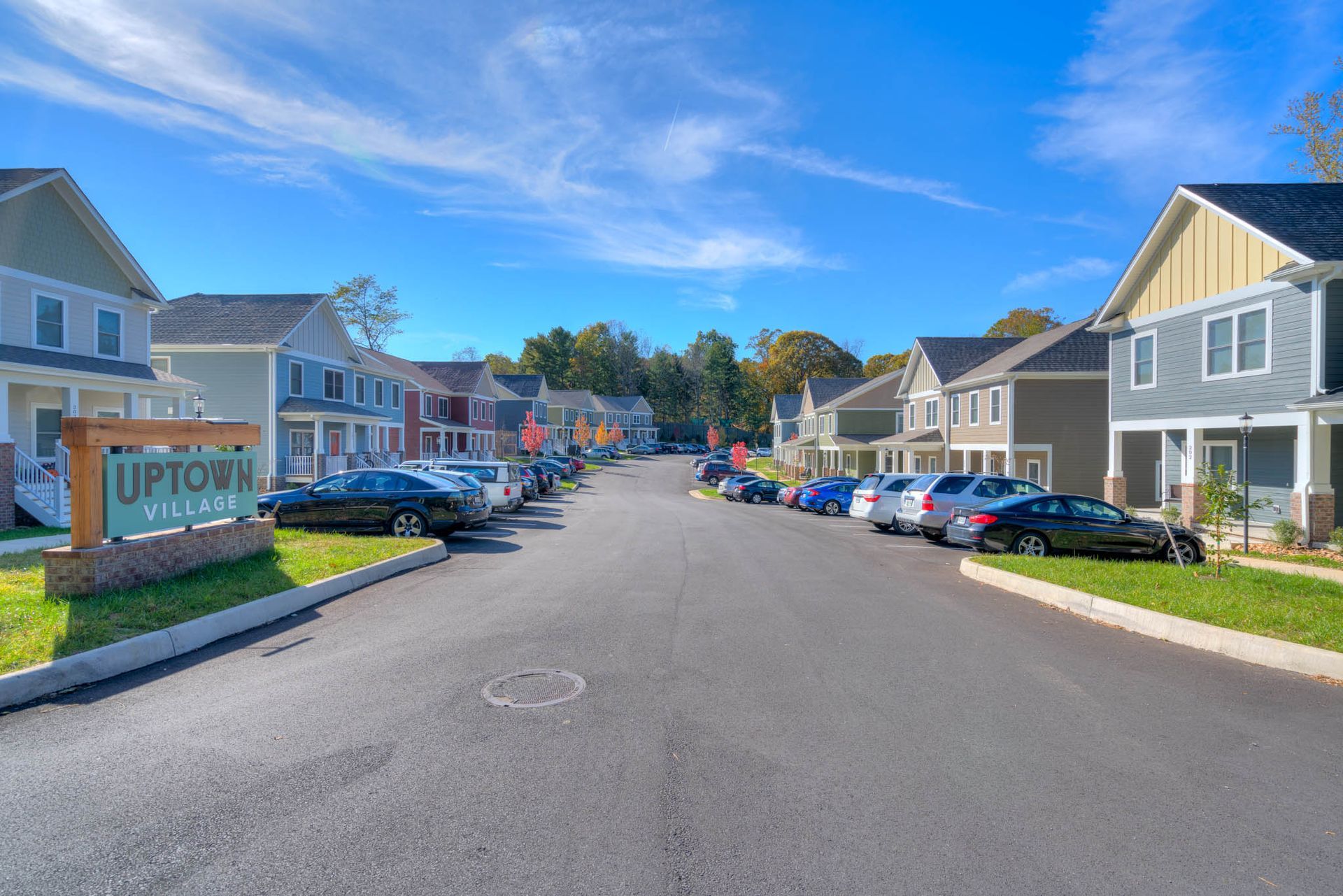 A street in Uptown Village with colorful houses and parked cars. Sign reads "Uptown Village."