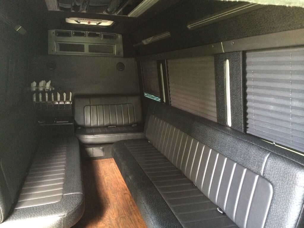 The inside of a van with black seats and blinds