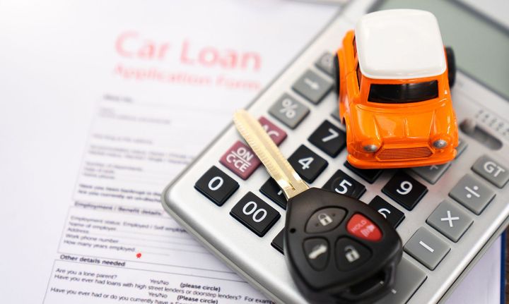 A toy car is sitting on top of a calculator next to a car key.