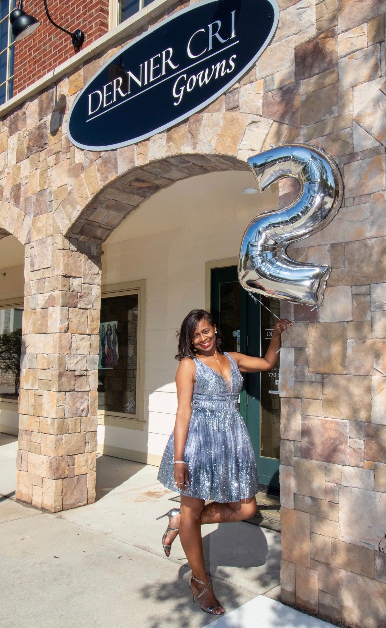 Bride in white gown ascends stone stairs toward a large church. Bright sunlight, lush greenery.
