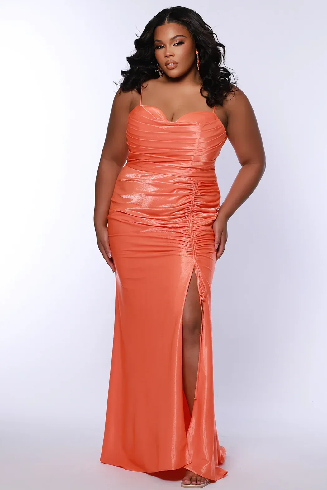 Bride in white gown with veil, holding bouquet, standing on stone steps, with building in the background.
