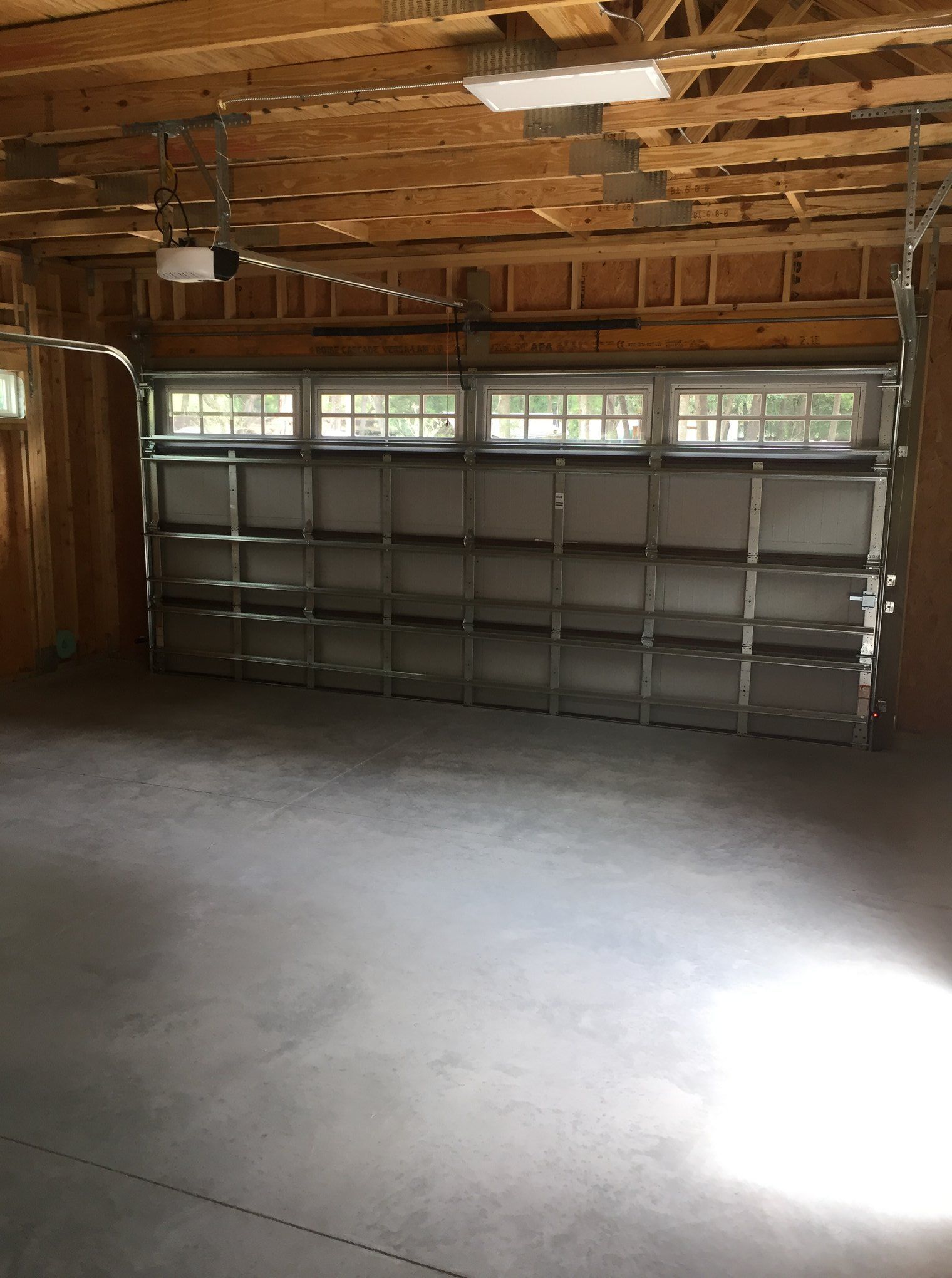 An empty garage with a large garage door and a window.