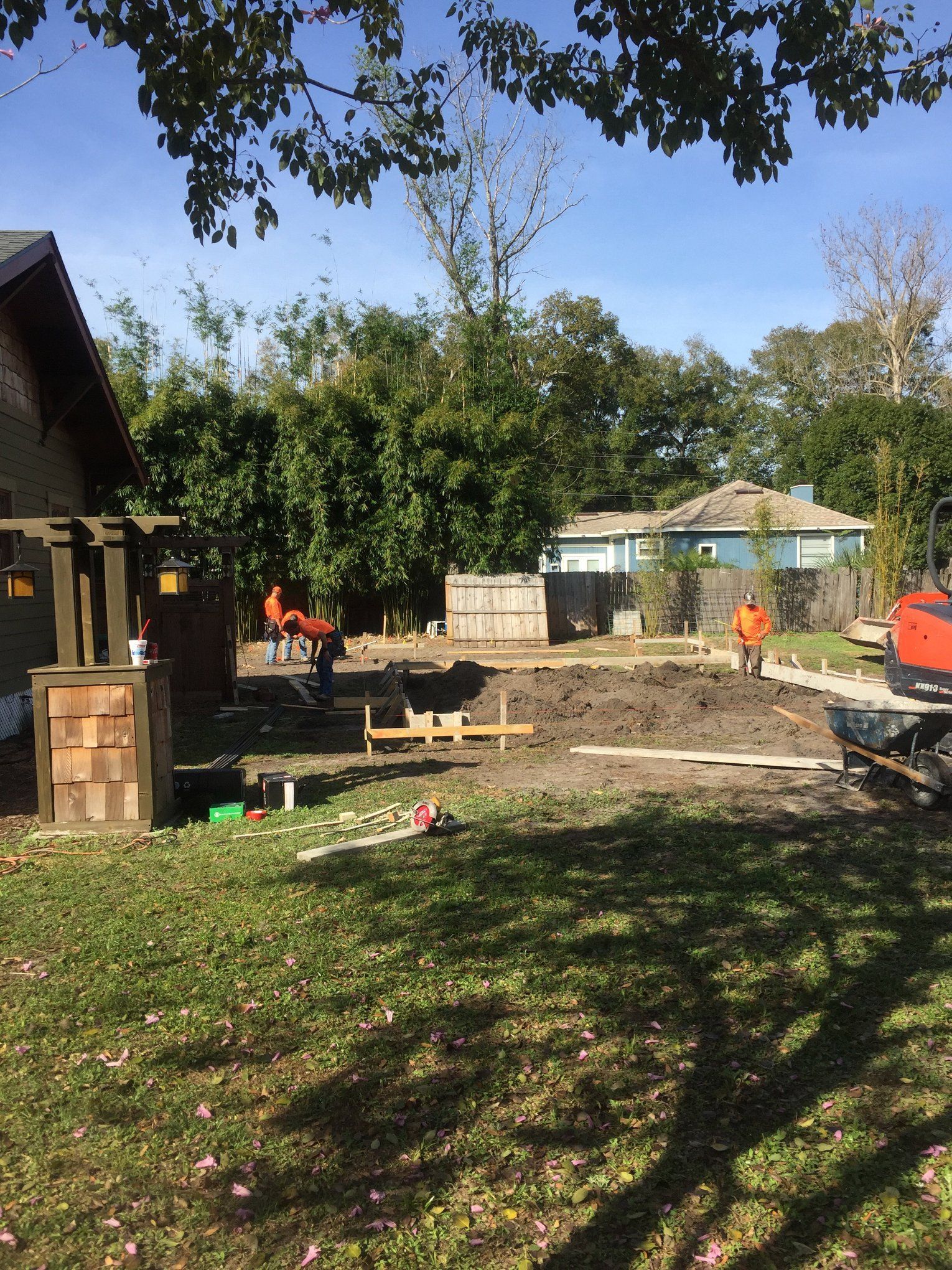 A construction site with a house in the background and a tractor in the foreground.