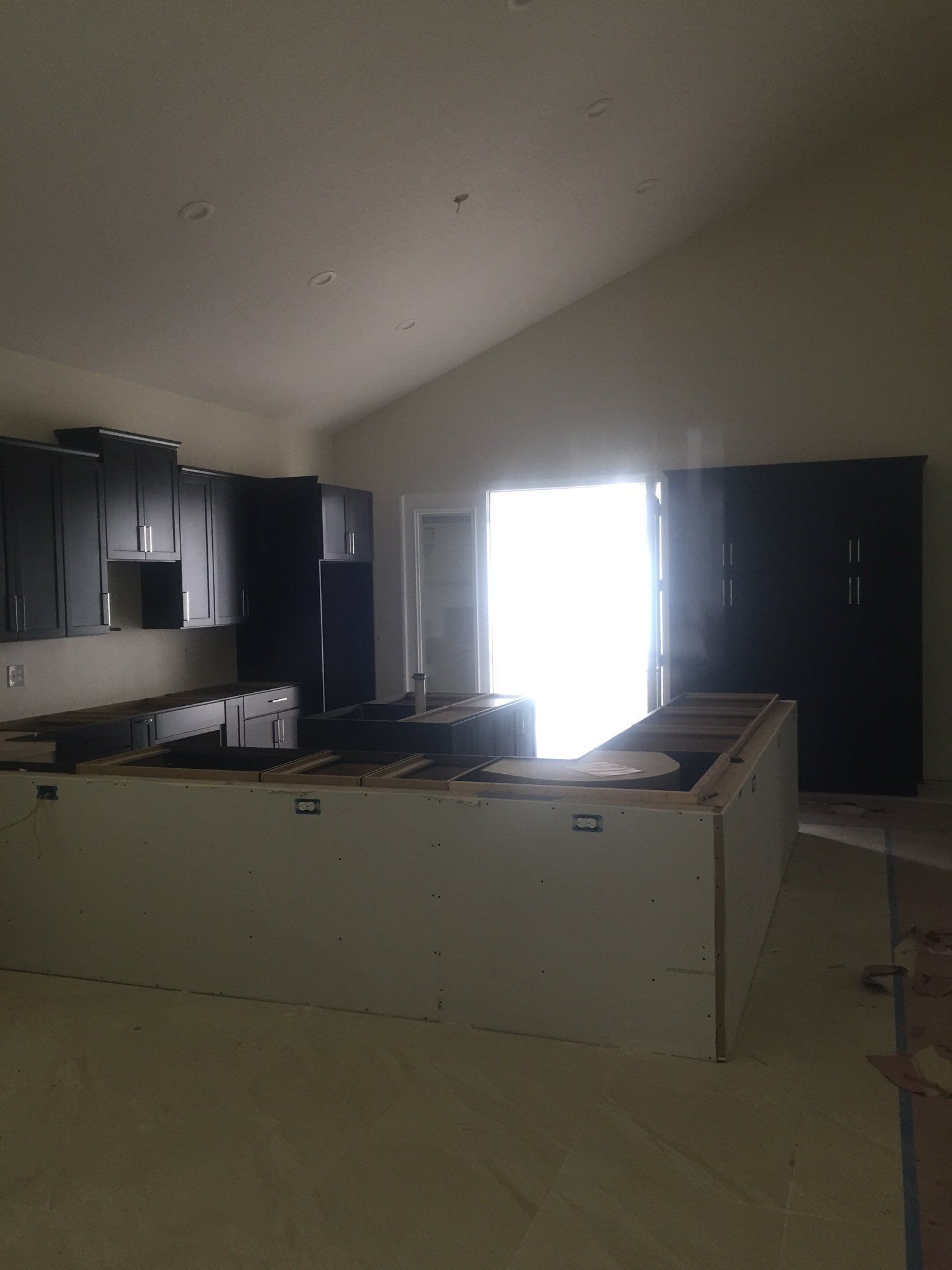 An empty kitchen with black cabinets and a large window
