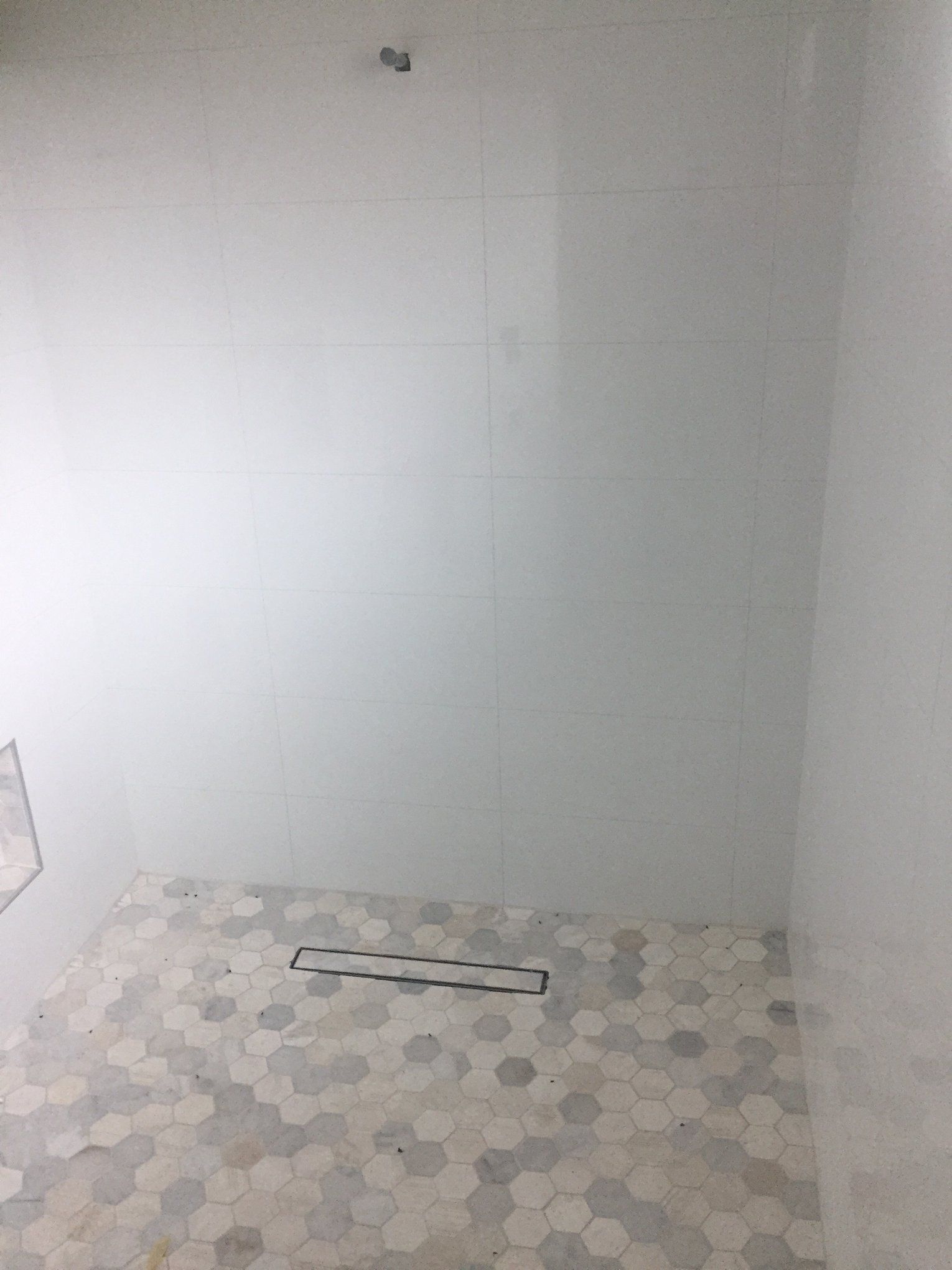 A bathroom with white tiles and a walk in shower.