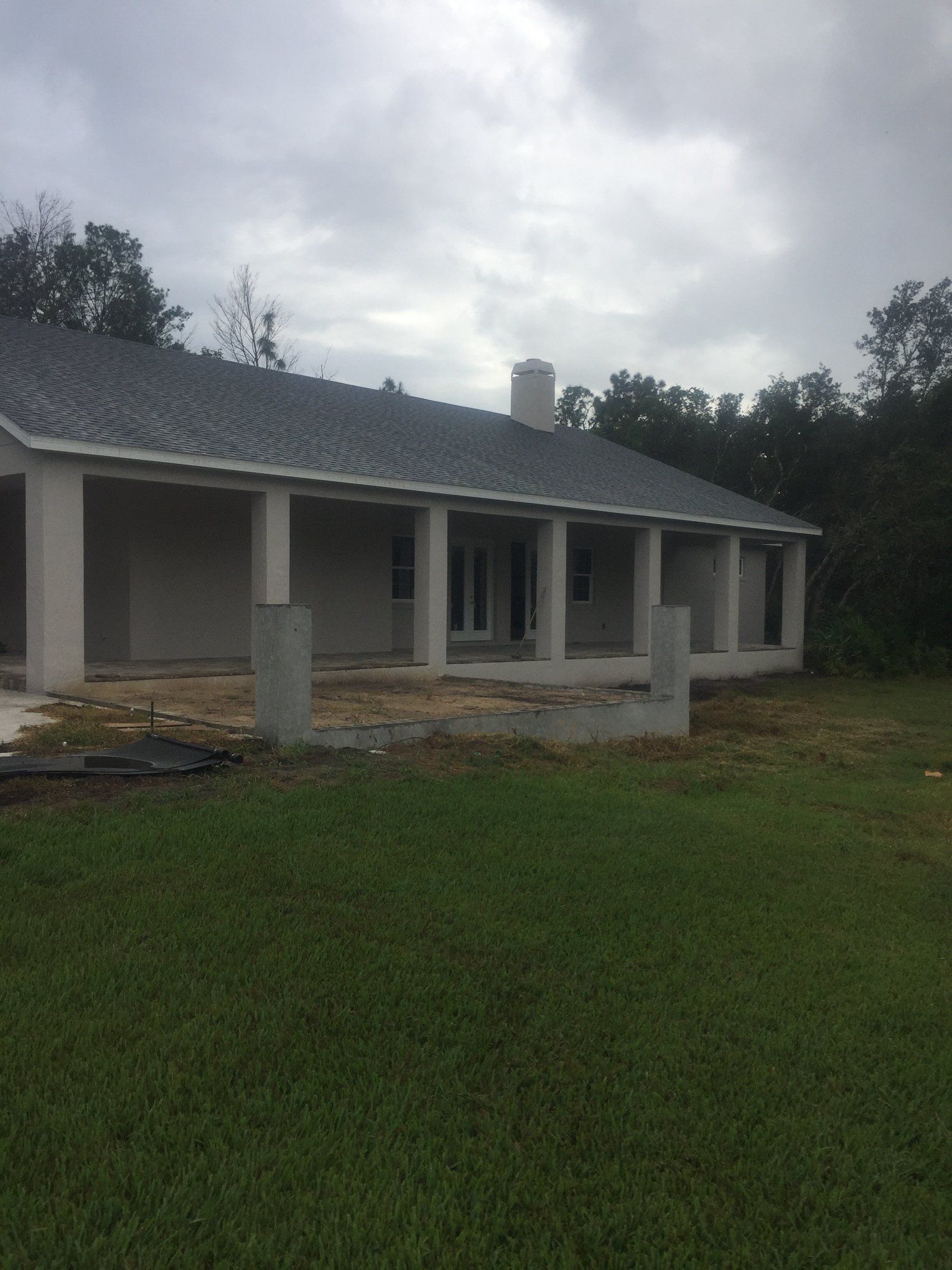 A house with a gray roof is sitting in the middle of a lush green field.