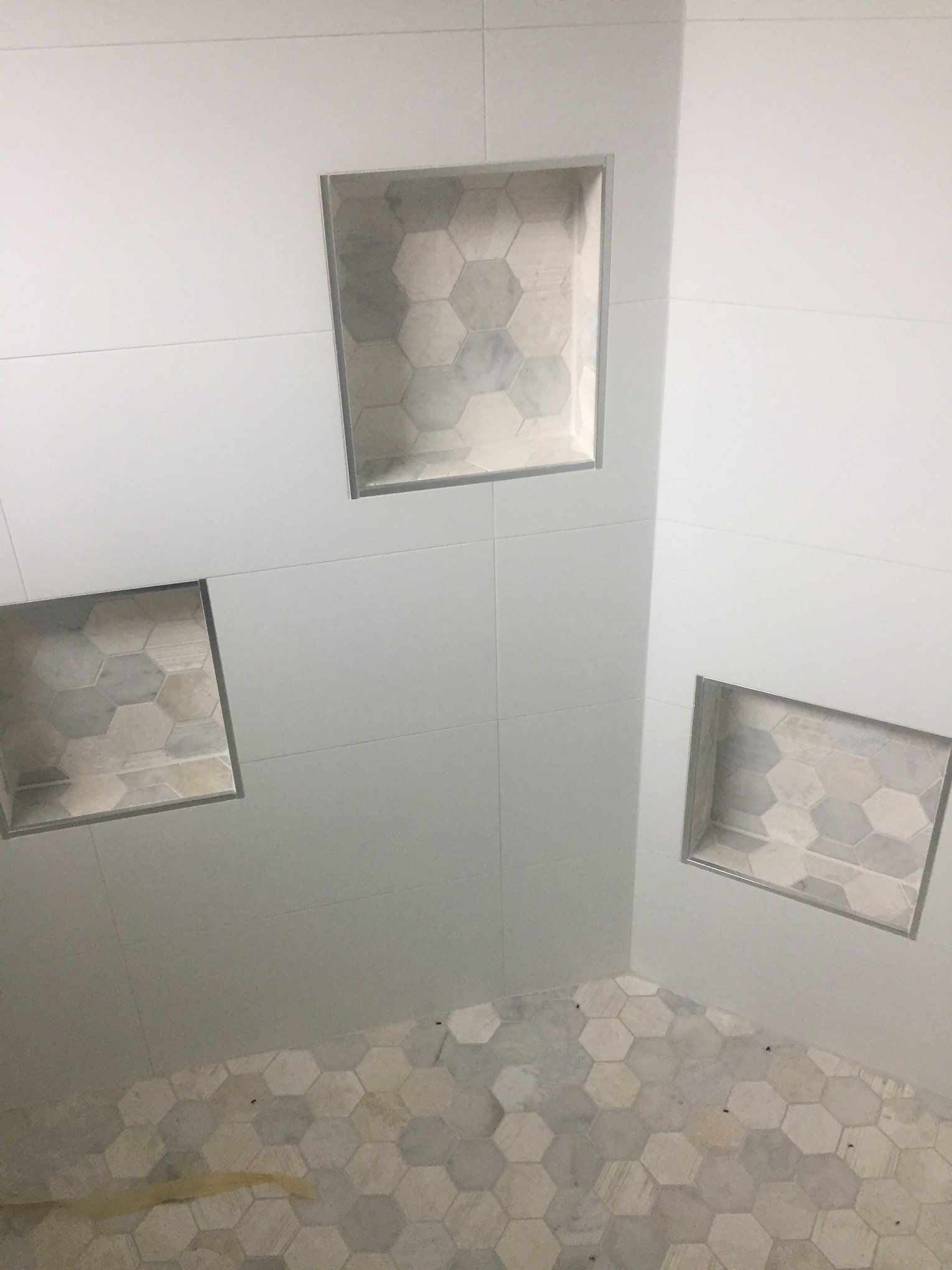 A bathroom with three shower niches and a tiled floor.