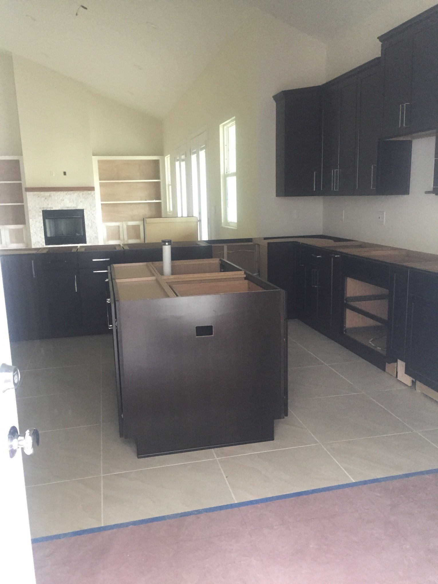 An empty kitchen with black cabinets and a large island in the middle.
