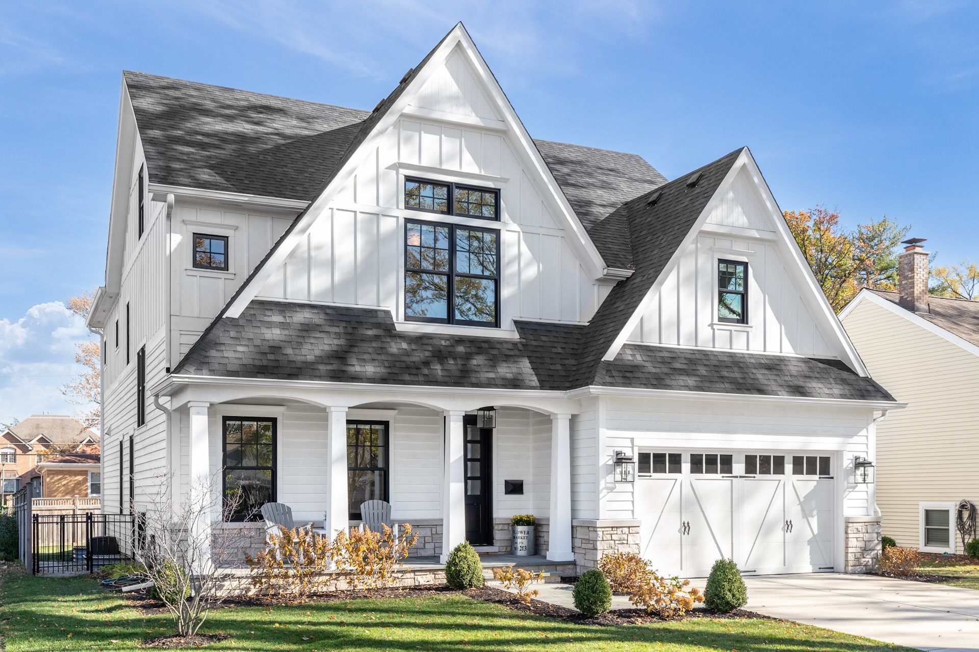 A large white house with a black roof and a porch.