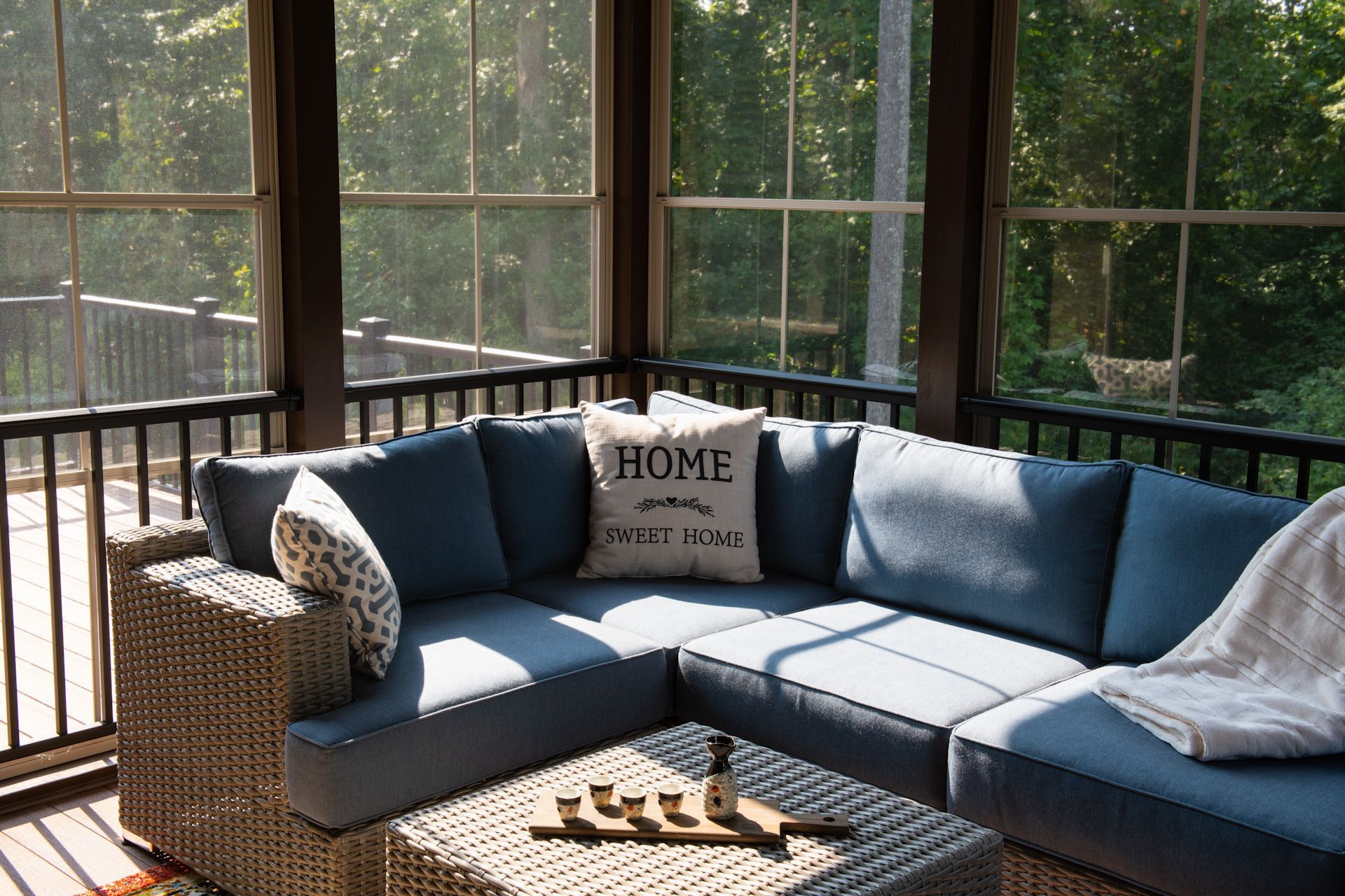 A screened in porch with a blue sectional couch and a coffee table.