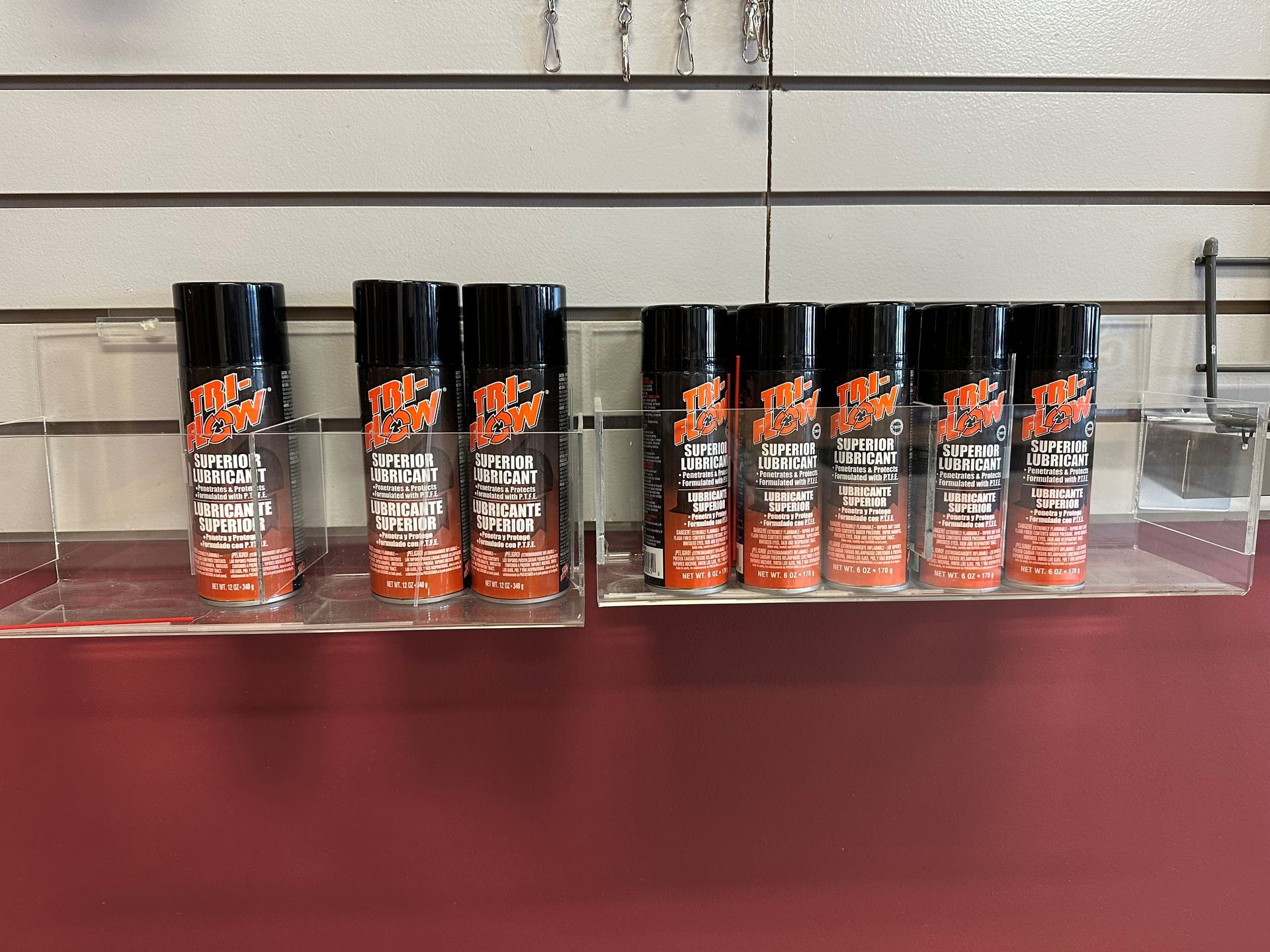 A row of spray bottles are lined up on a shelf.