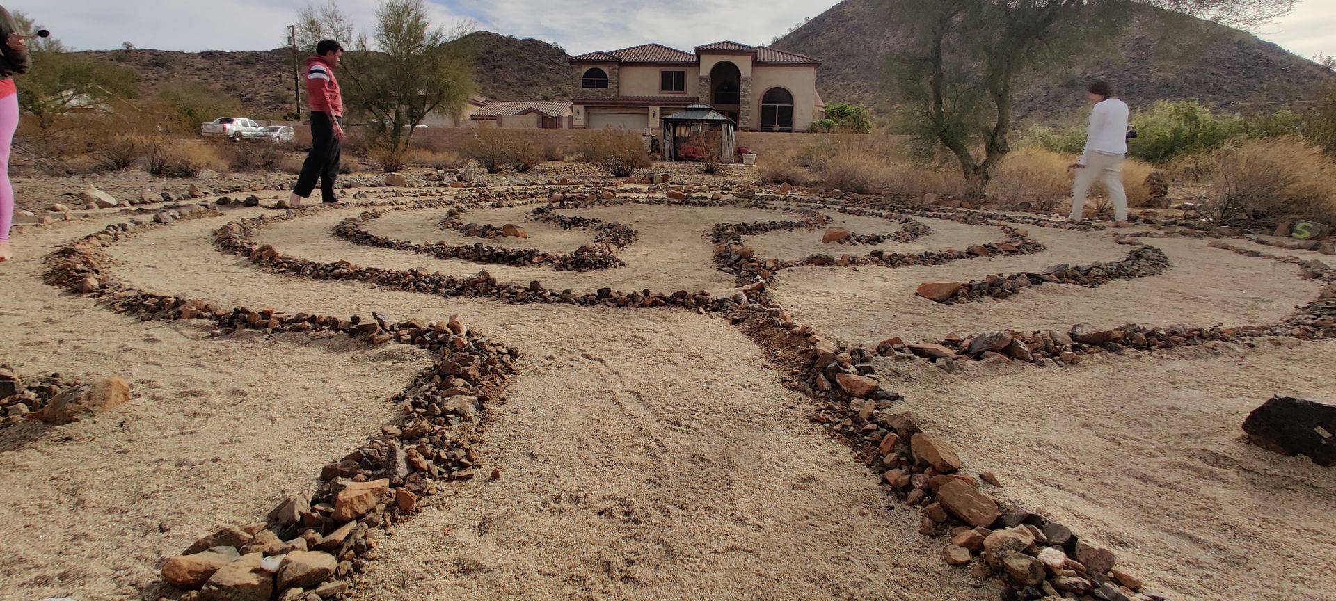 A group of people are standing around a labyrinth made of rocks in the desert.