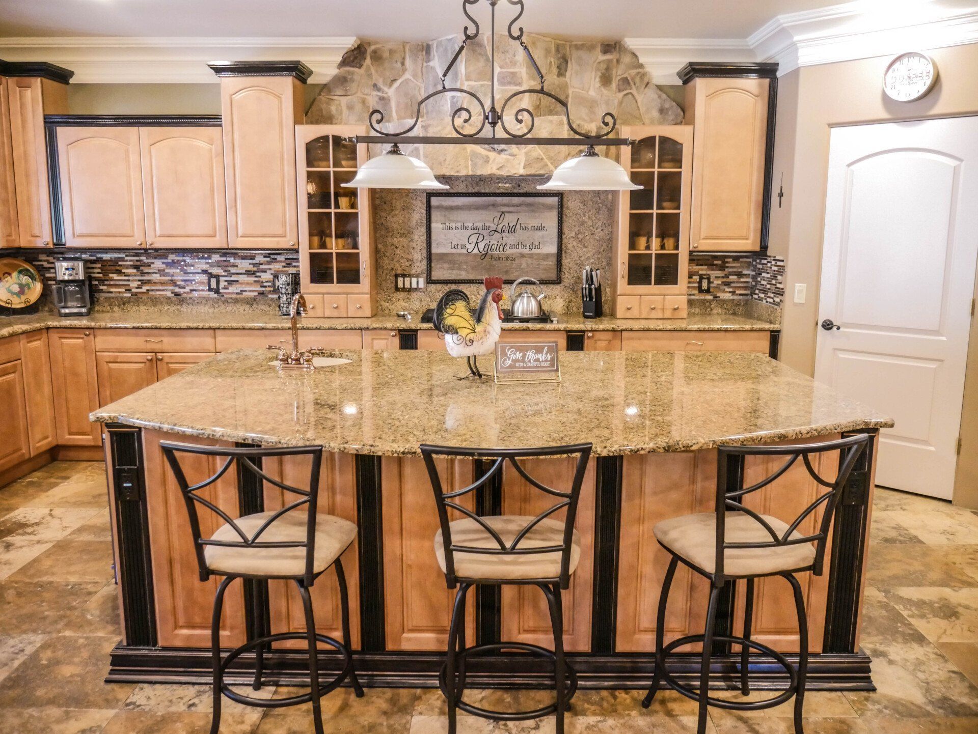 A kitchen with a large island and three bar stools.