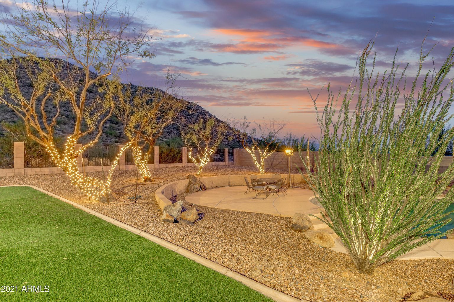 The trees are decorated with lights and there is a sunset in the background.