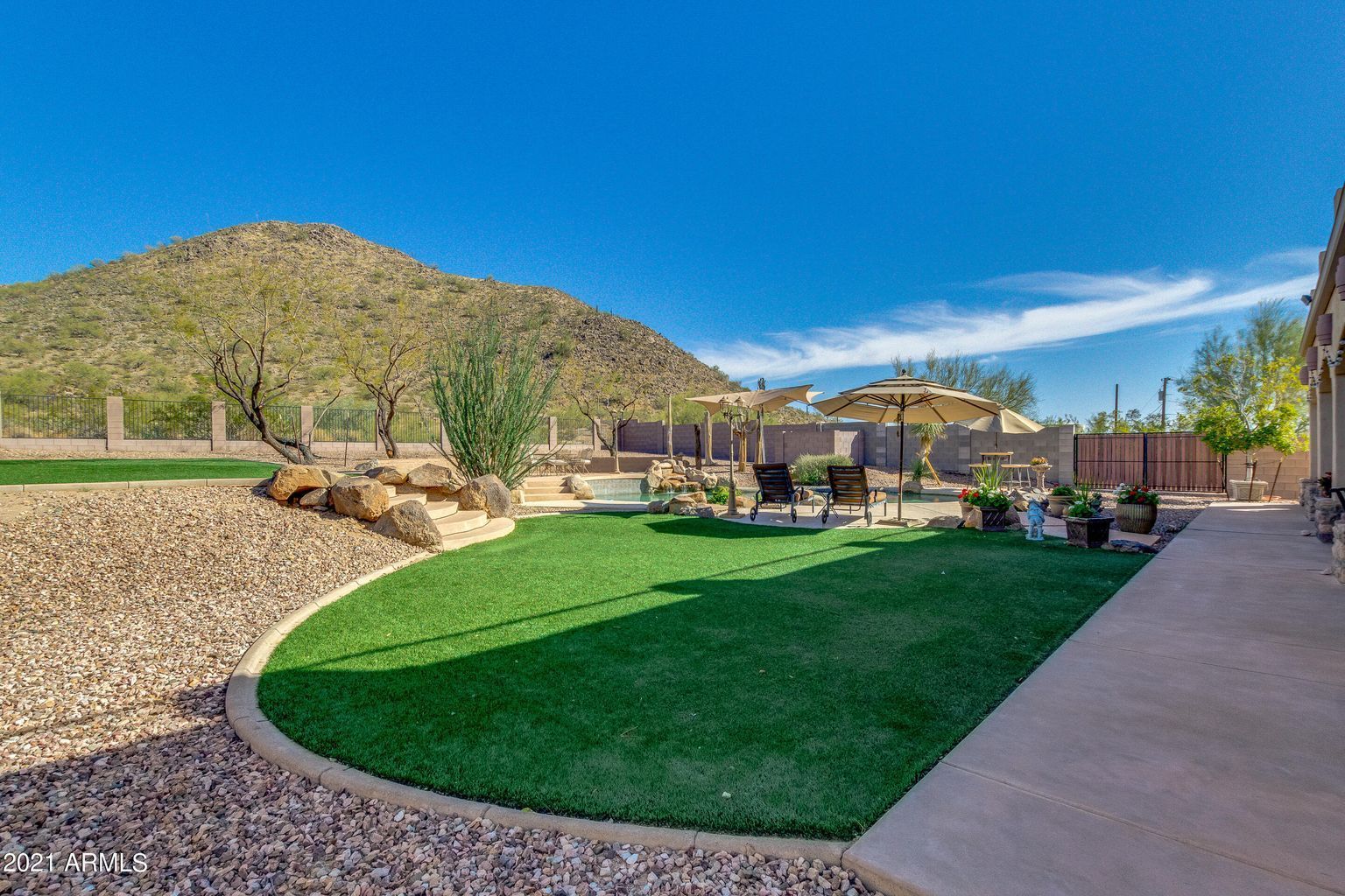 A backyard with a lot of grass and a mountain in the background.