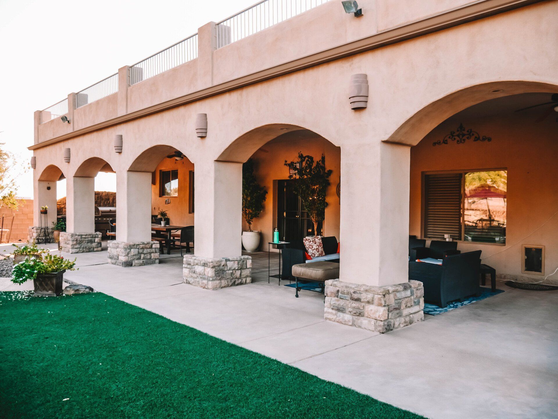 A patio with arches and a lawn in front of it