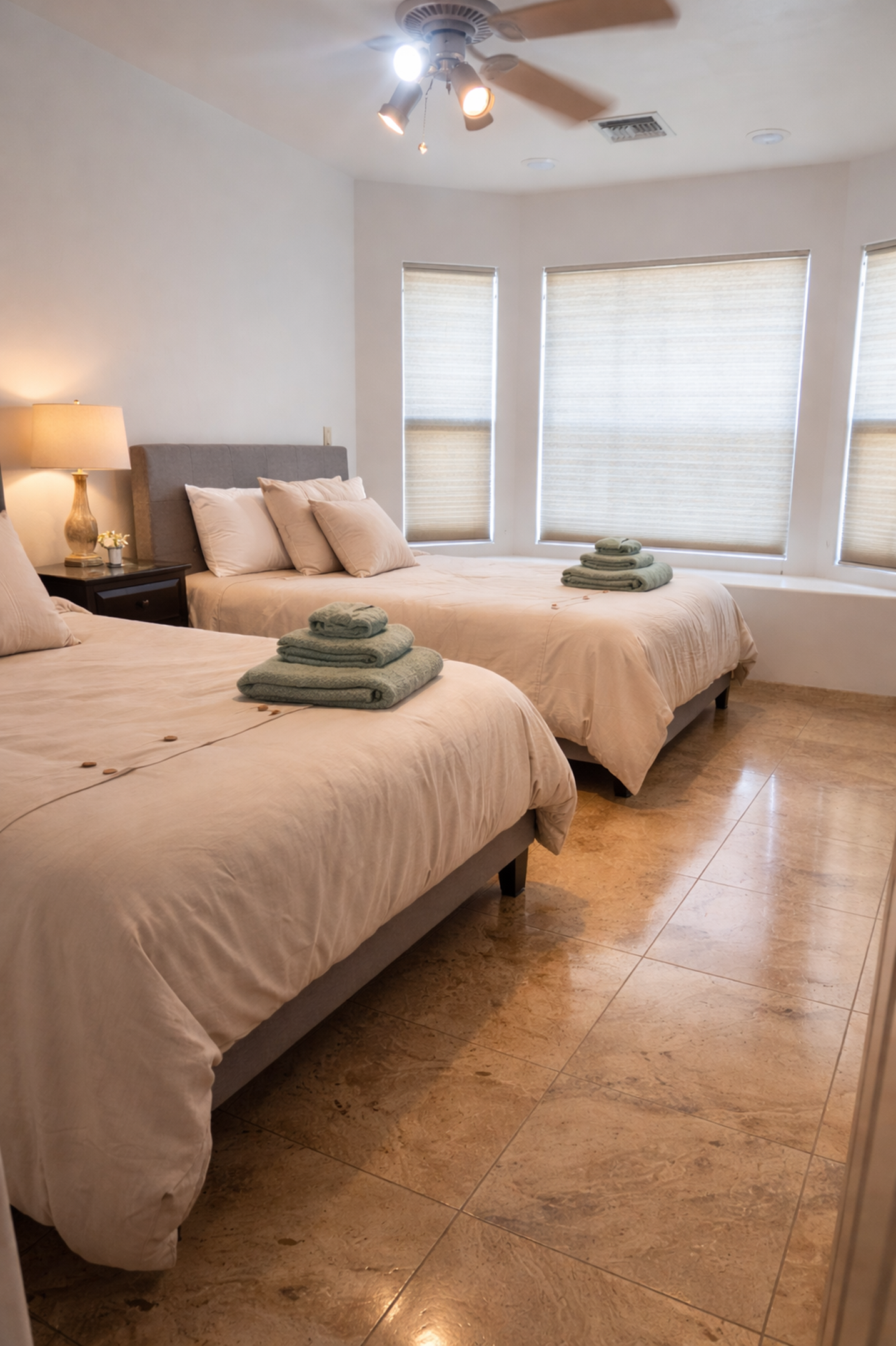 A bedroom with two beds and a ceiling fan.