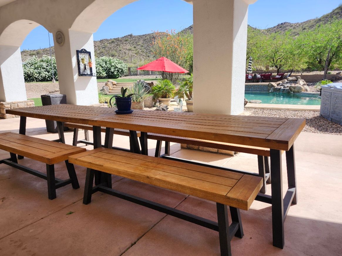 A wooden table and benches on a patio with a ceiling fan.