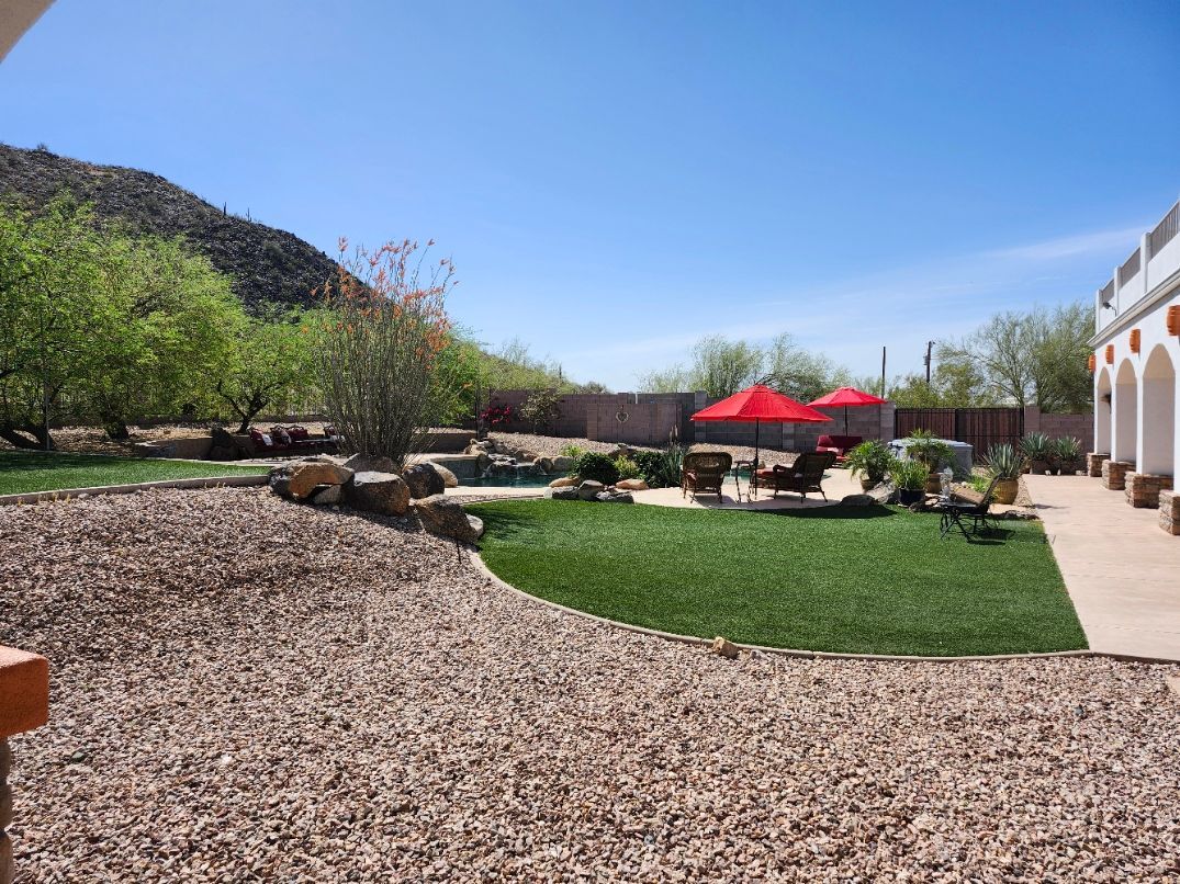 A large swimming pool with umbrellas and chairs in a backyard with mountains in the background.