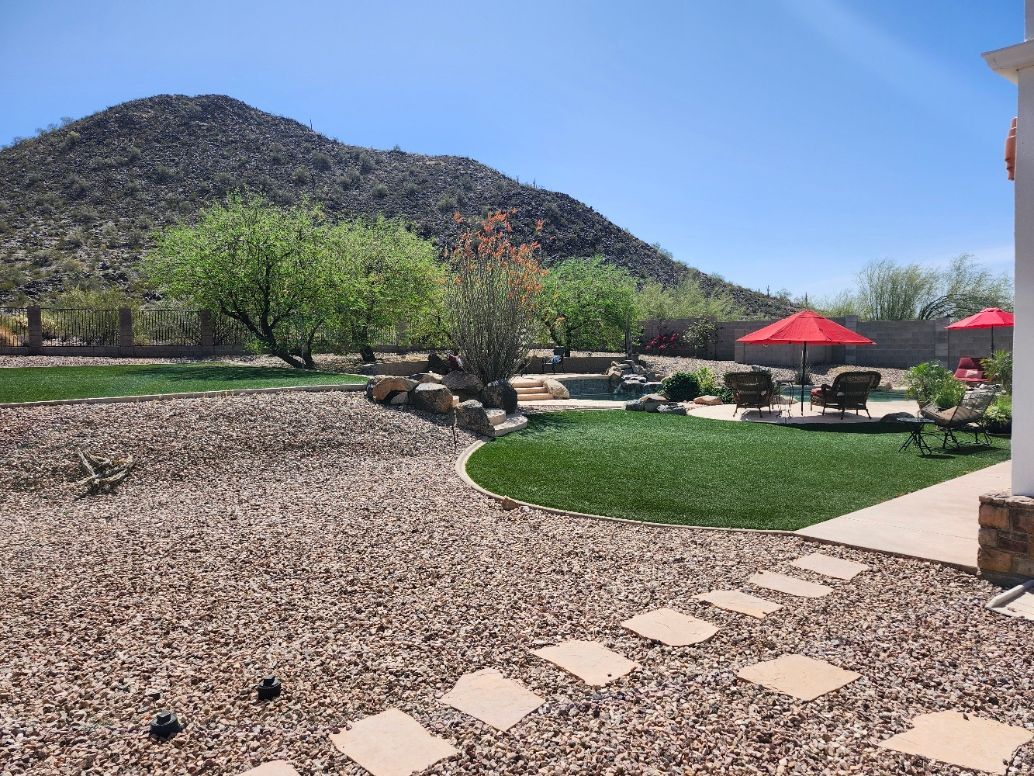 A large lawn with umbrellas and chairs in front of a house with a mountain in the background.