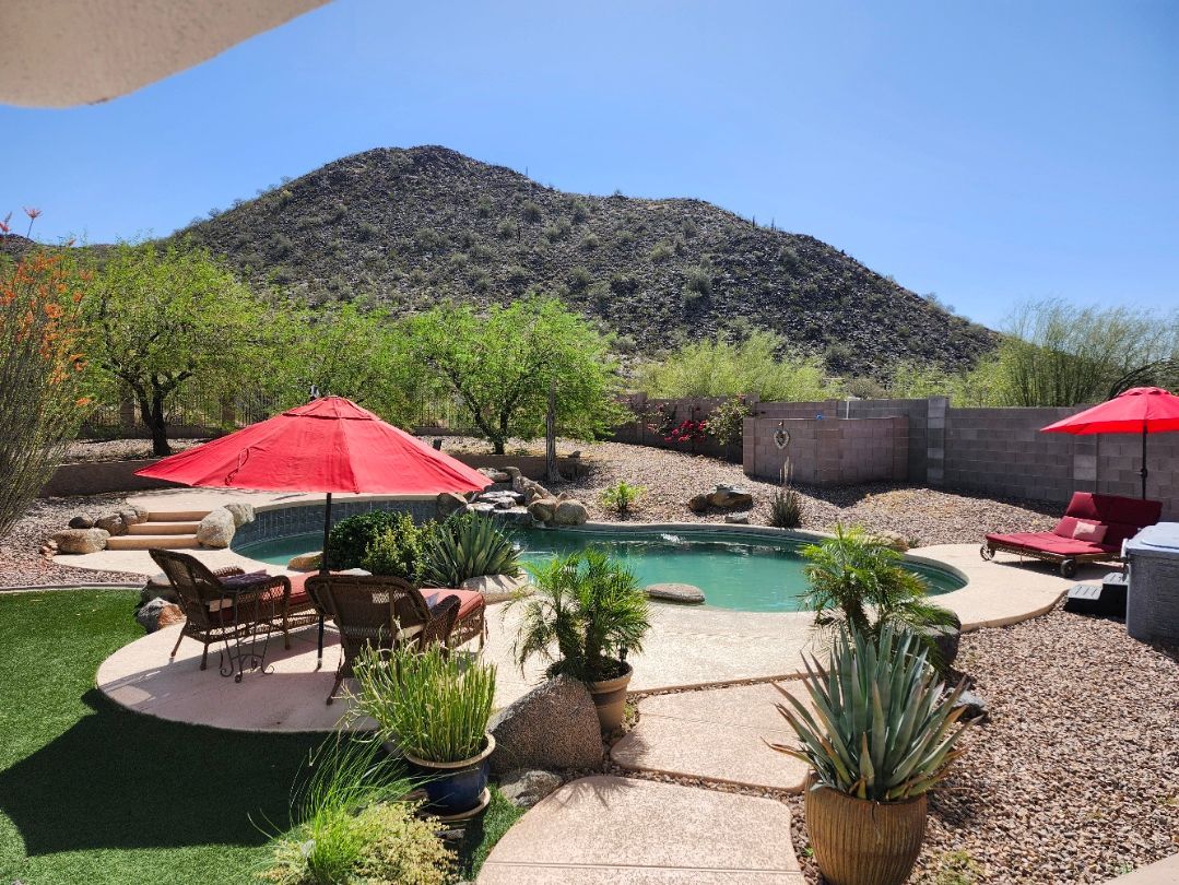 A large swimming pool in the backyard of a house with mountains in the background.