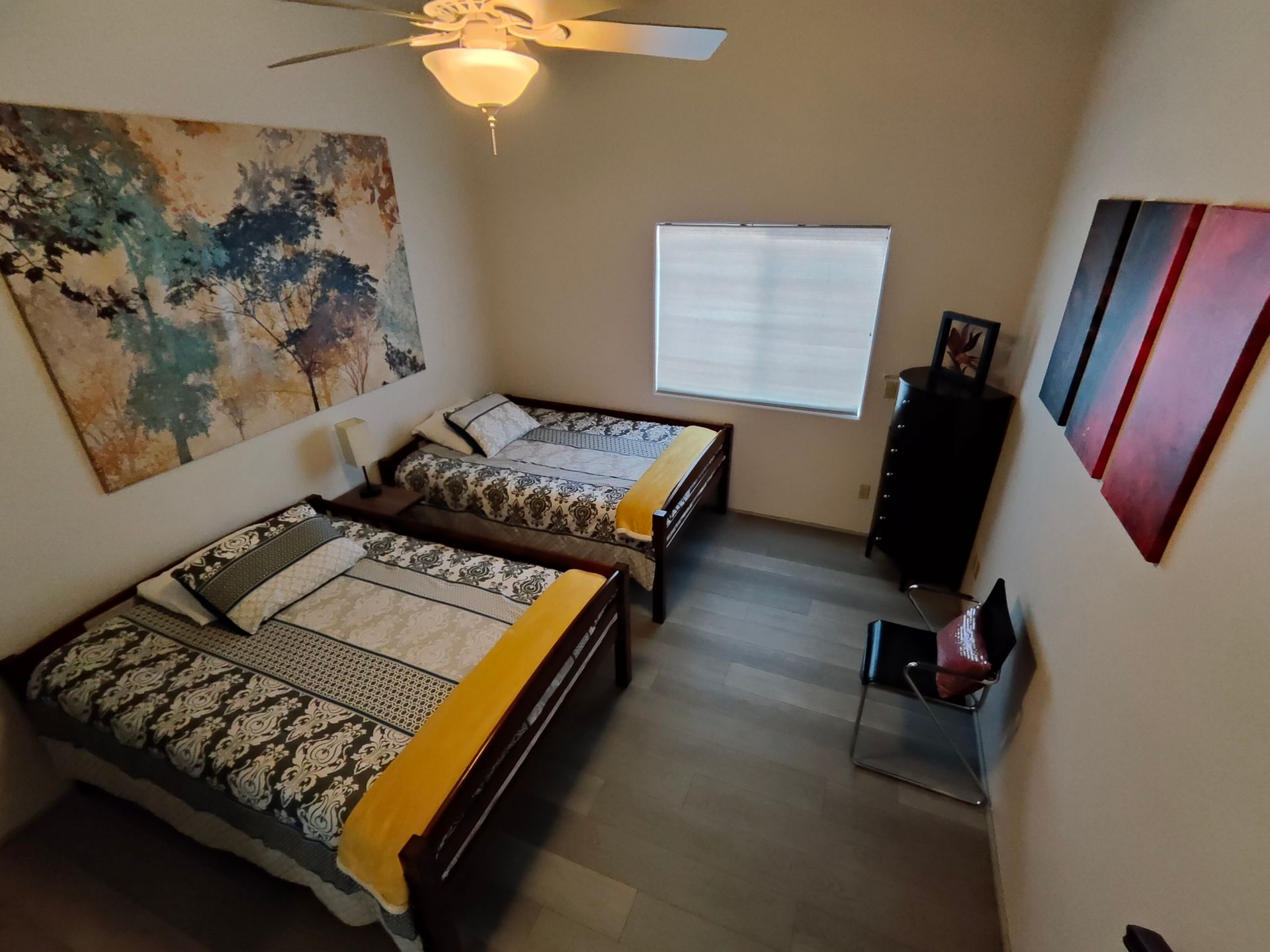 A bedroom with two beds and a ceiling fan