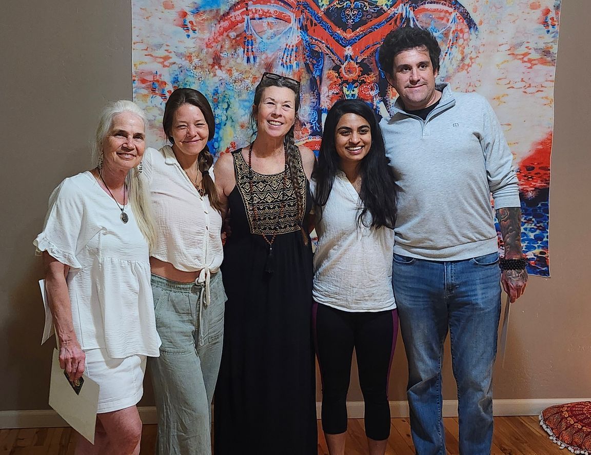 A group of people are posing for a picture in front of a painting.