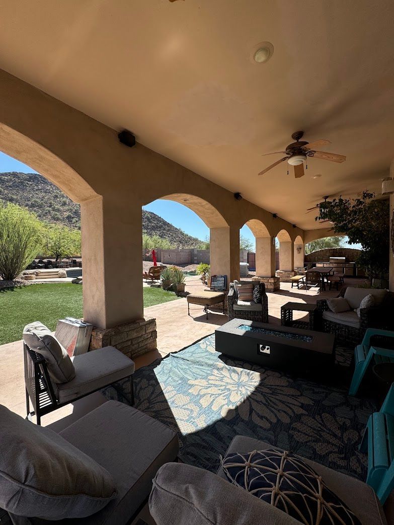 A patio with a lot of furniture and a ceiling fan