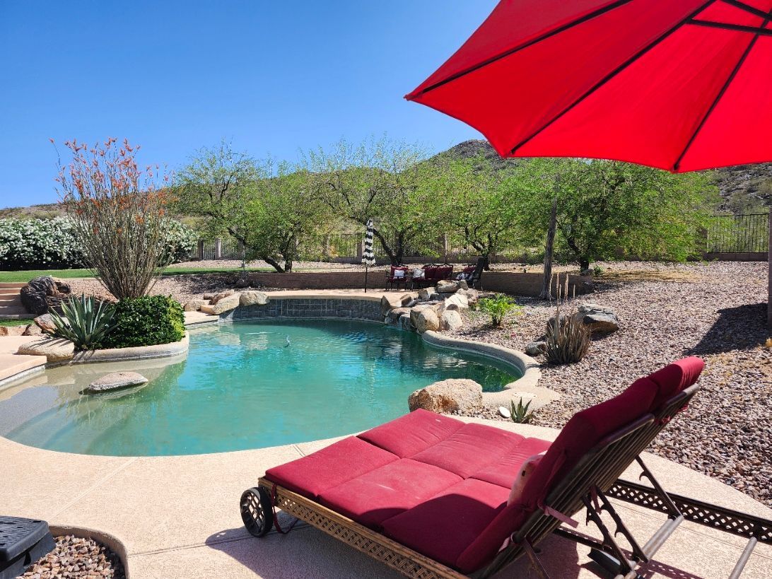 A large house with a pool and patio area in front of it.