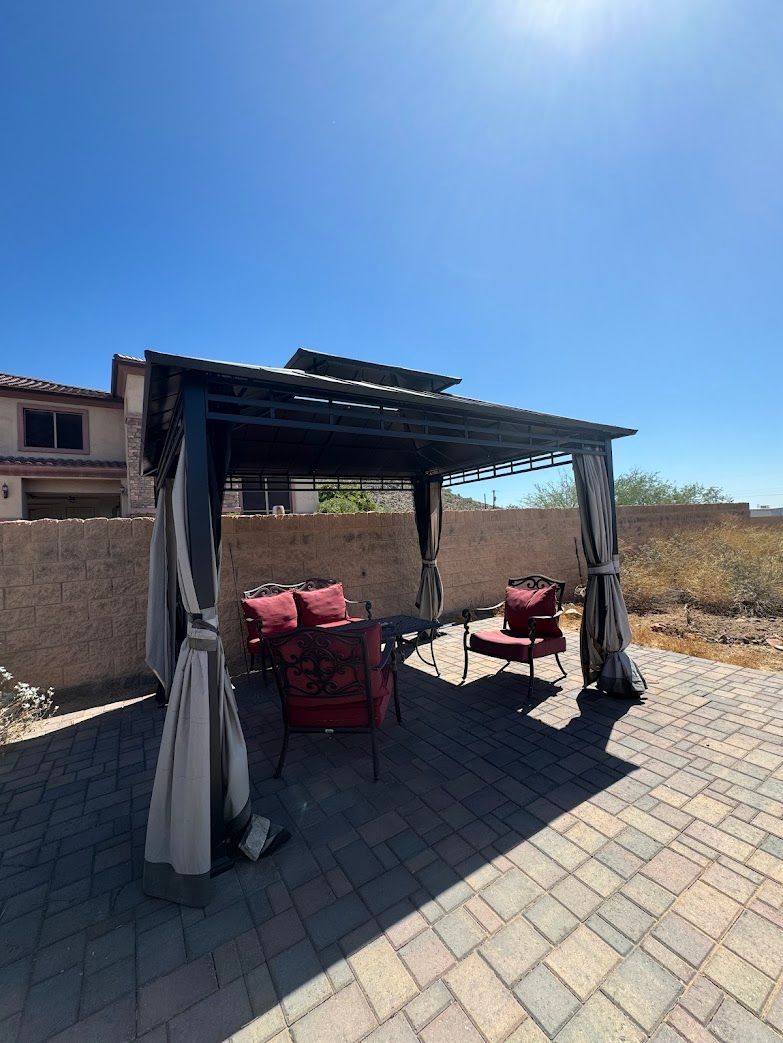 There is a pergola with a couch and chairs underneath it.